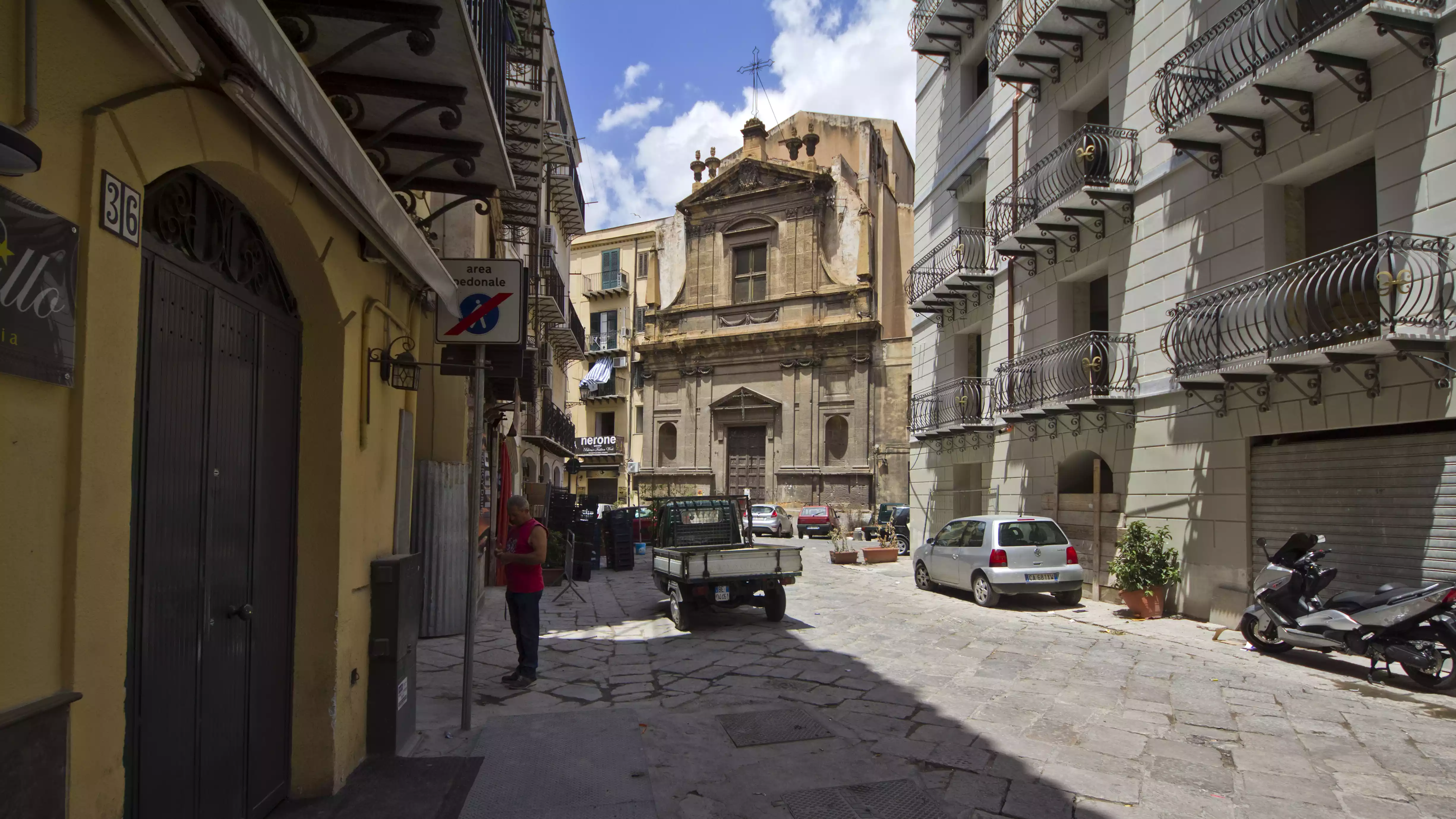 centro storico degrado pavimentazione rovinata auto parcheggiate strada dissestata aree pedonali occupate edifici antichi